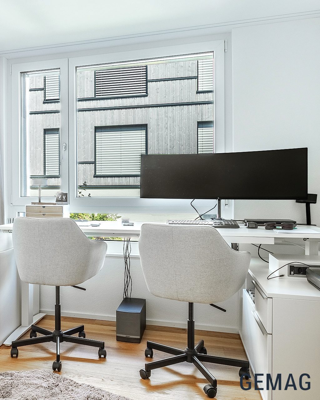 Bürozimmer mit weissem Einbauschrank, zwei Bürostühlen und Schreibtisch am Fenster, Parkettboden.
