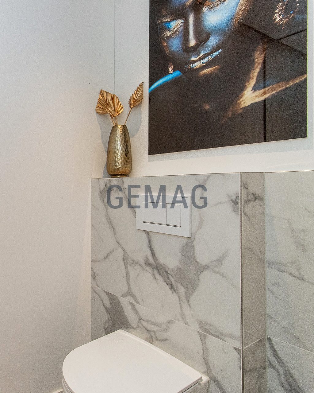 Gäste-WC mit wandhängendem WC, Marmor-Verkleidung, Unterputzspülung und goldener Deko-Vase.