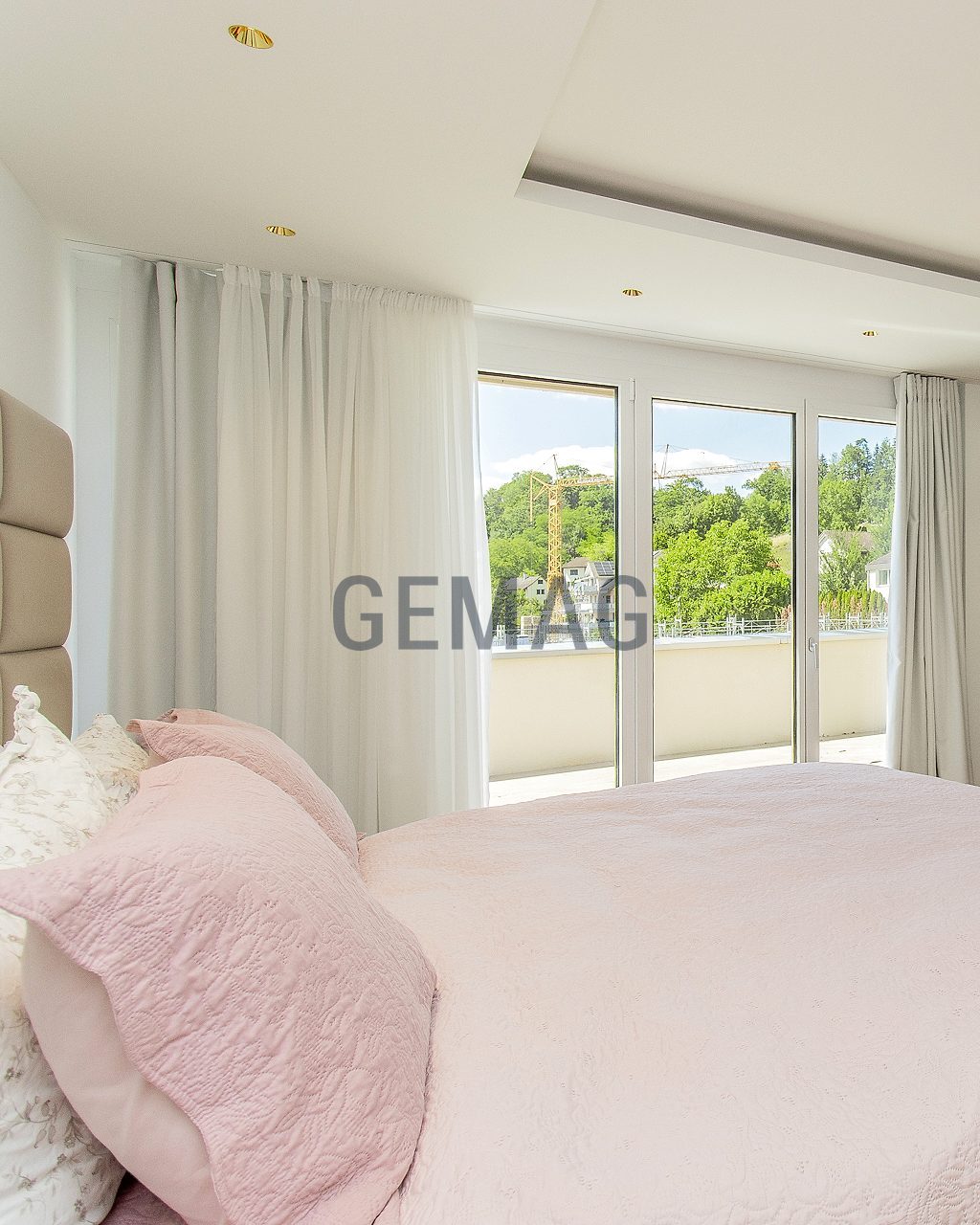 Schlafzimmer mit Doppelbett, weisser Kommode, Kassettendecke und grosser Balkontür mit Grünblick.