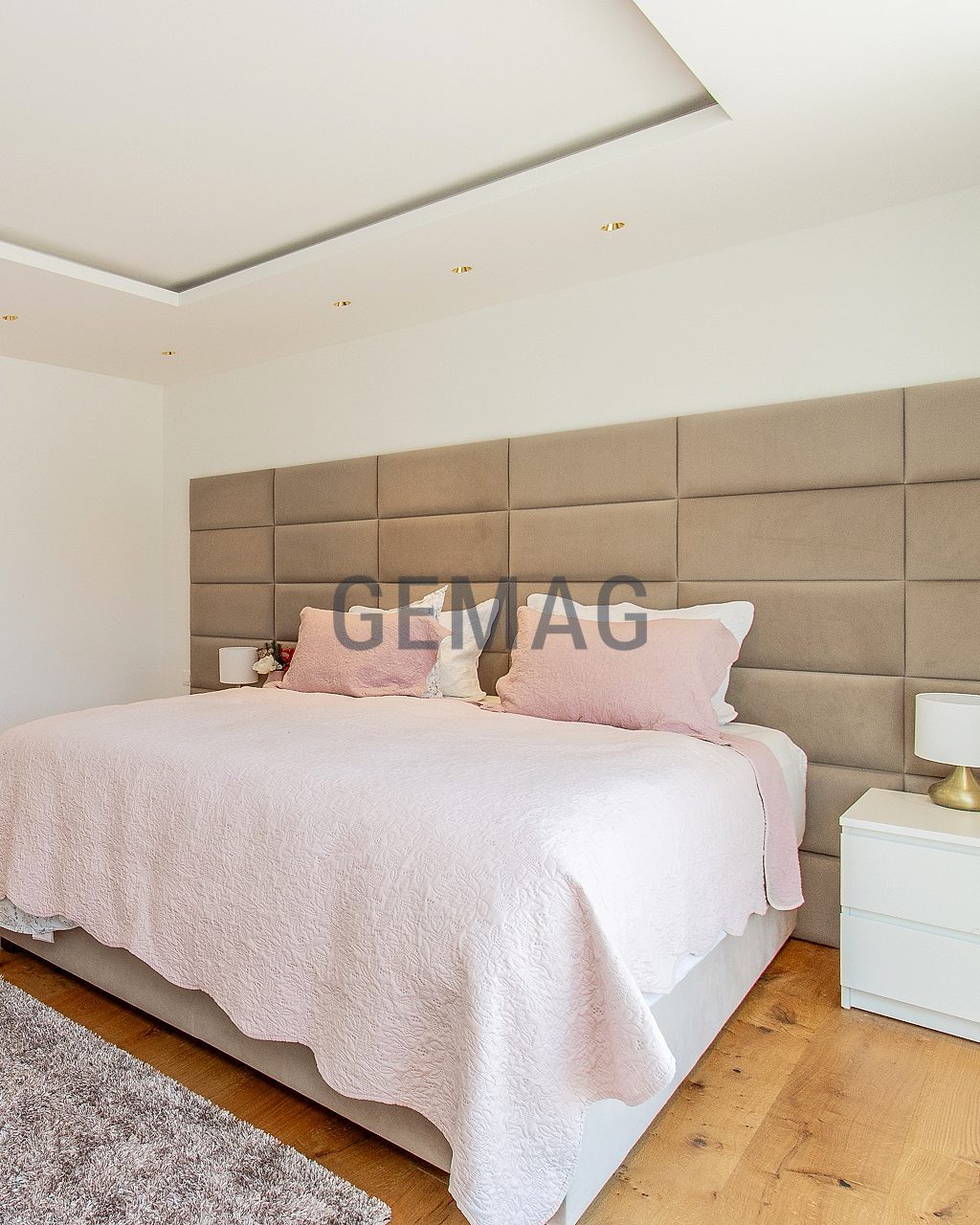 Schlafzimmer mit gepolstertem Kopfteil, Parkettboden und offenem Ankleidebereich, Totale.