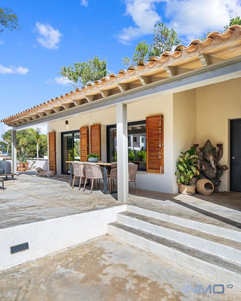 Überdachte Außenterrasse mit Lounge- und Essbereich, Holzläden und mediterranem Ziegeldach, Blick auf die Fassade.
